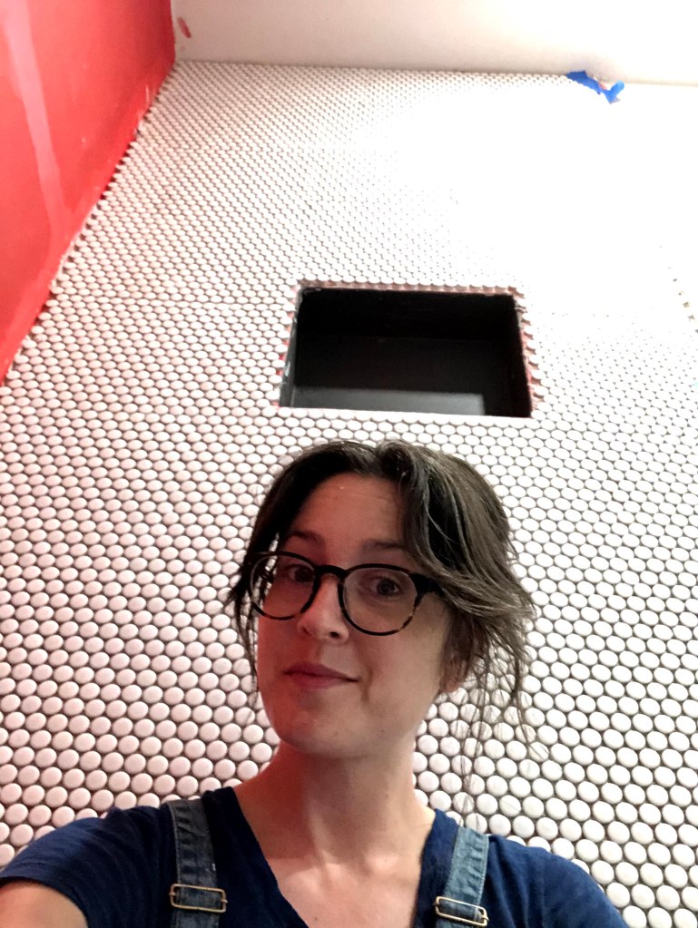 White penny tile up on one wall of the shower